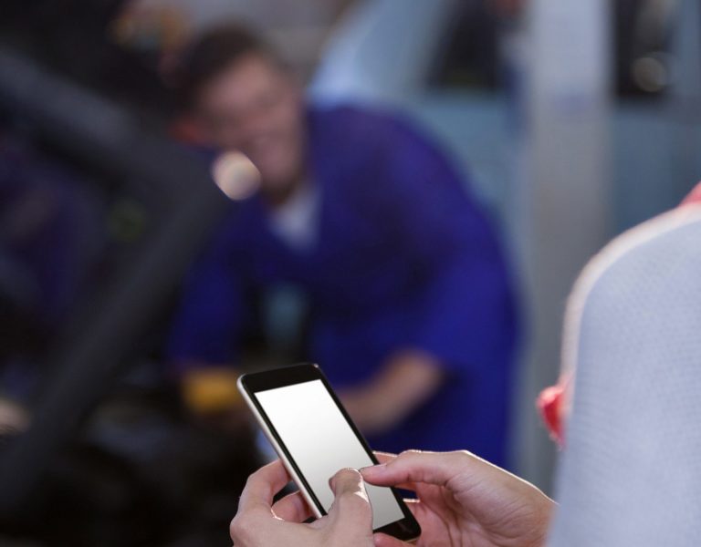 Customer text messaging on the mobile at the repair garage